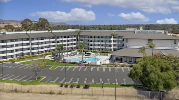 Ein mehrstöckiges Hotel mit Schwimmbad, Parkplatz und Blick auf die umliegende Landschaft.