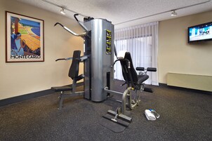 Un gimnasio con equipo de ejercicio, un televisor y un cartel en la pared.