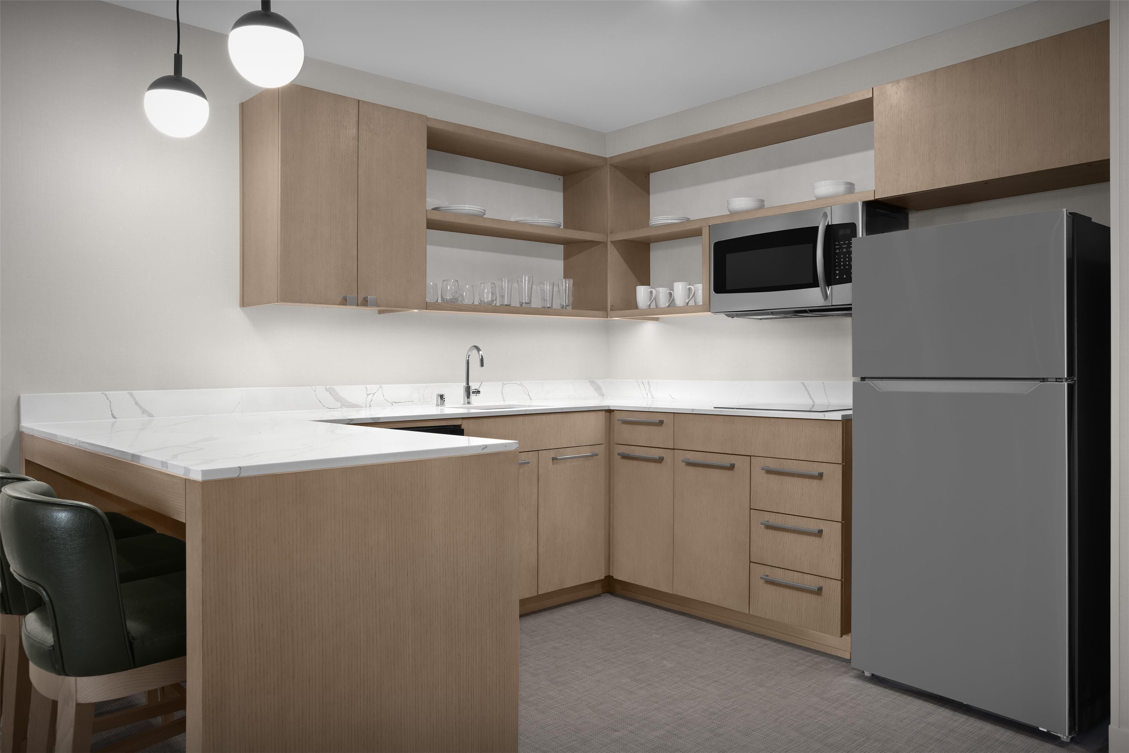 Una cocina moderna con una isla central, microondas integrado y refrigerador.