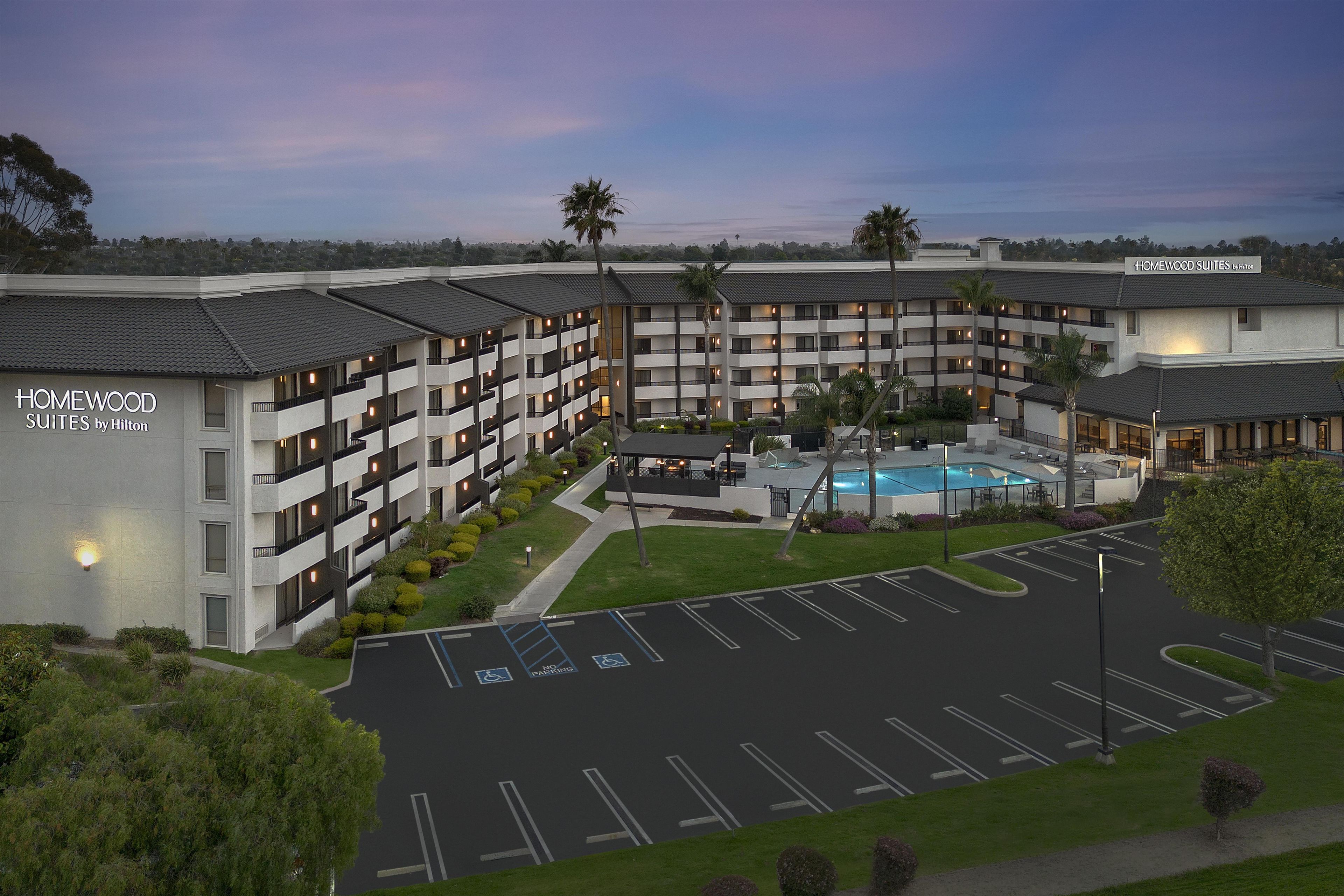 A hotel with multiple floors, a swimming pool, and a parking lot.