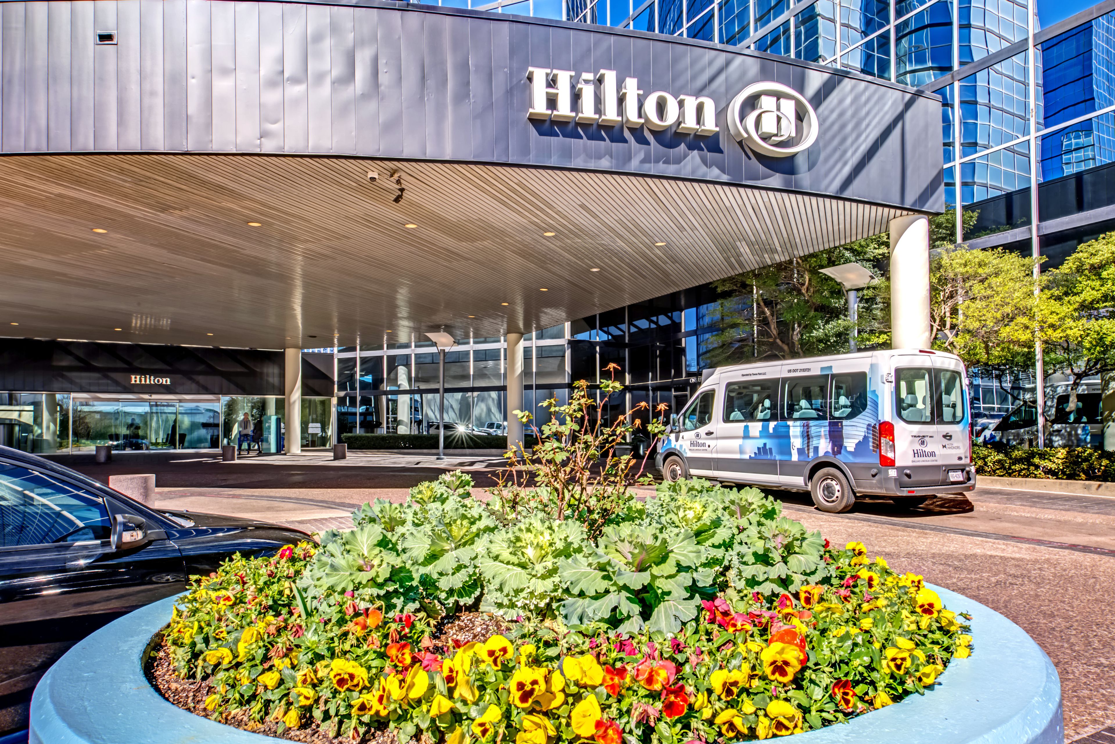 L’entrée d’un hôtel Hilton, avec un grand parterre fleuri devant.
