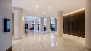 A spacious lobby with polished marble floors, white pillars, and a modern design. - Hilton Dallas Lincoln Centre by the Galleria (Dallas)