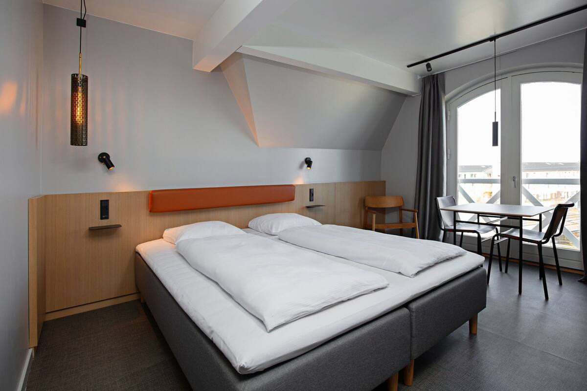 Ein modernes Hotelzimmer mit einem großen Bett, einem Schreibtisch und Blick auf die Stadt.