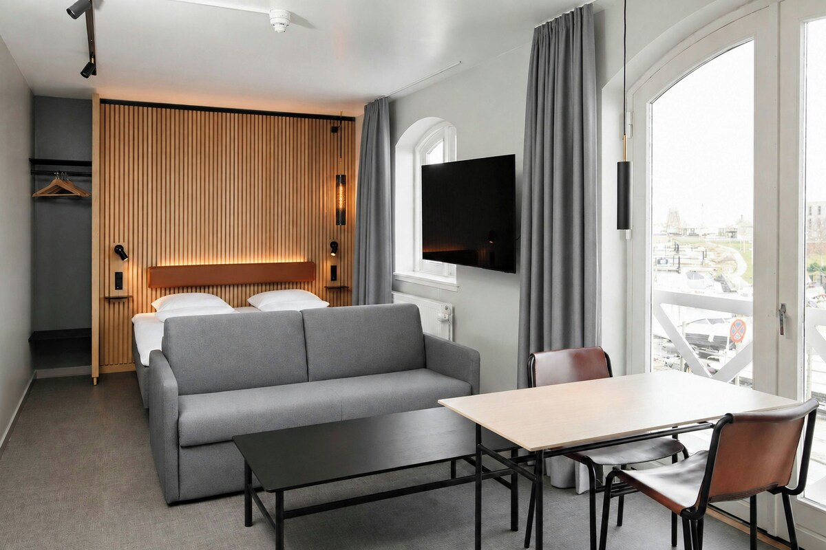 A modern hotel room with a sofa, a table, and a TV.
