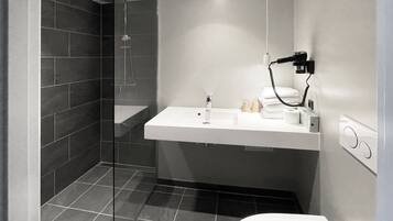 Un bagno moderno con cabina doccia in vetro, un lavandino bianco e un water.