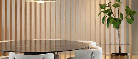 Un comedor moderno con una mesa redonda, sillas tapizadas de color gris, una lámpara colgante y una planta en maceta.
