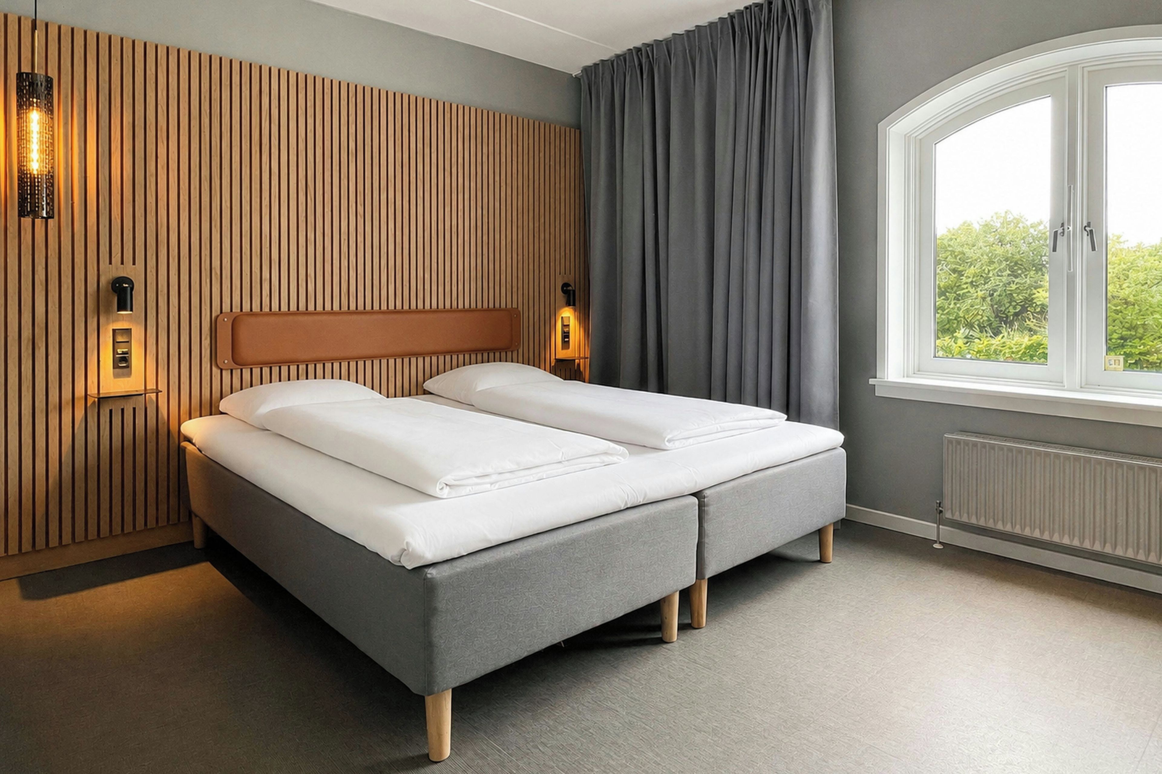 A double bed with a wooden headboard, two bedside tables, and a window with curtains.
