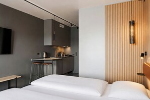 A modern bedroom with a bed, a small kitchenette, and a TV mounted on the wall. - Four Points Flex by Sheraton Køge (Koge)