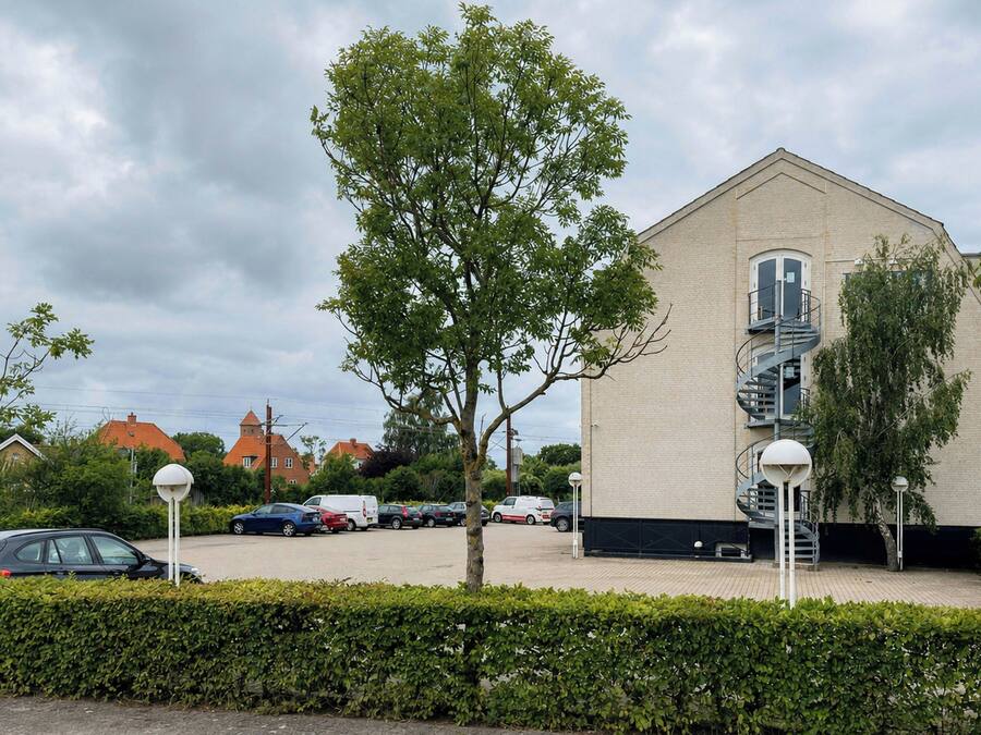 Un bâtiment doté d’un escalier en colimaçon, d’un parking et d’un arbre à l’avant.