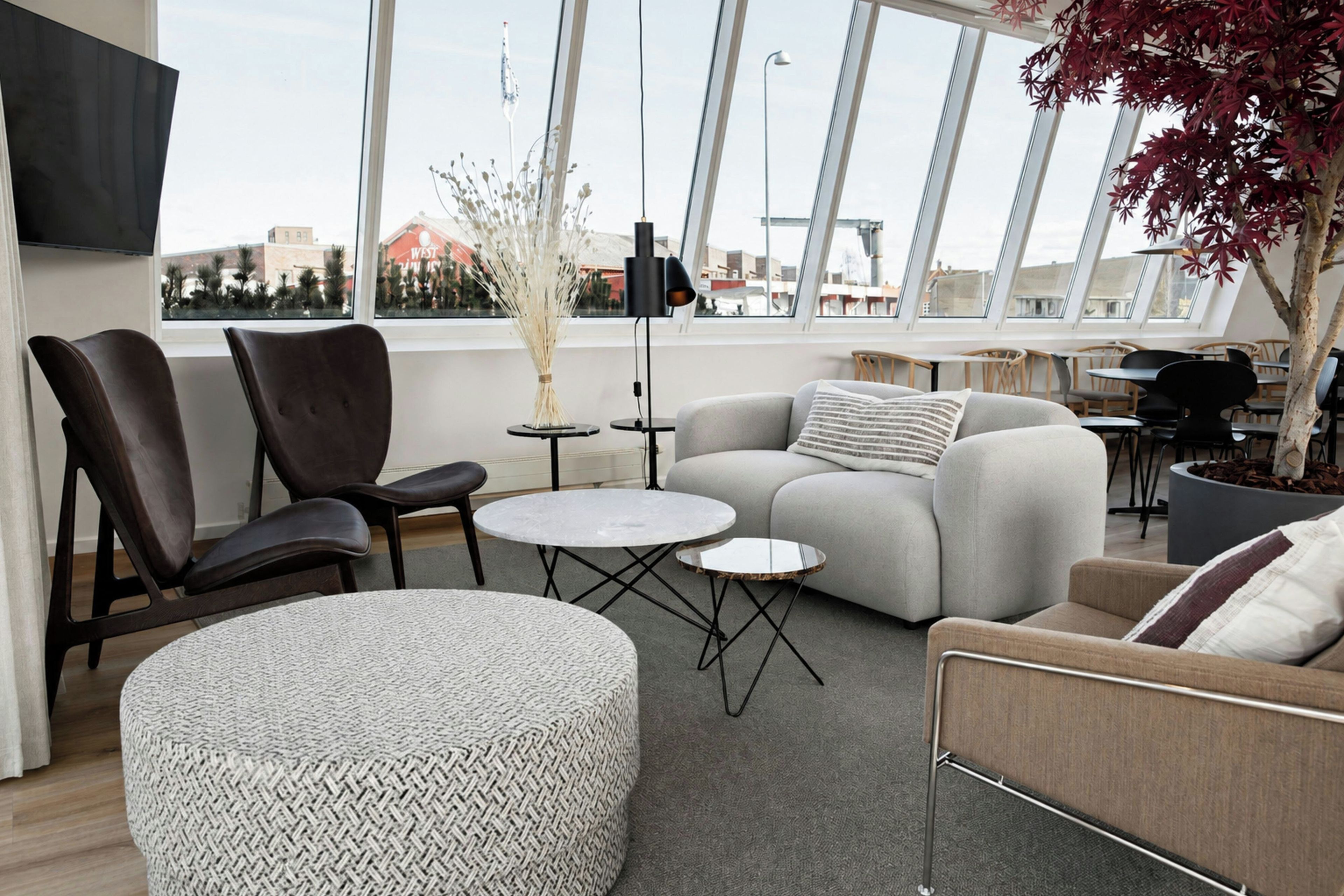 A modern living space with a sofa, chairs, a round ottoman, and a small table.