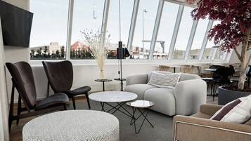 A modern living space with a sofa, chairs, a round ottoman, and a small table.