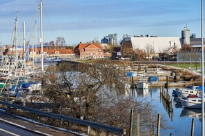 A marina with boats docked, a red building, and industrial structures in the background. - Four Points Flex by Sheraton Køge (Koge)