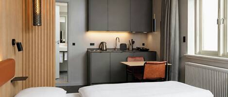 A hotel room with a bed, a desk, and a kitchenette.