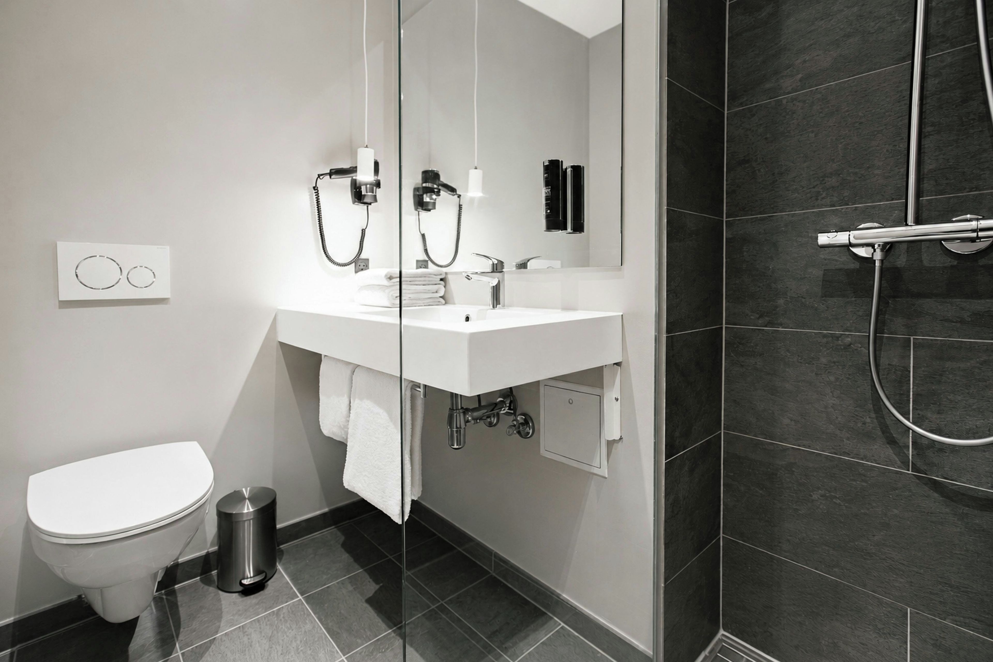 A modern bathroom with a toilet, sink, and shower.