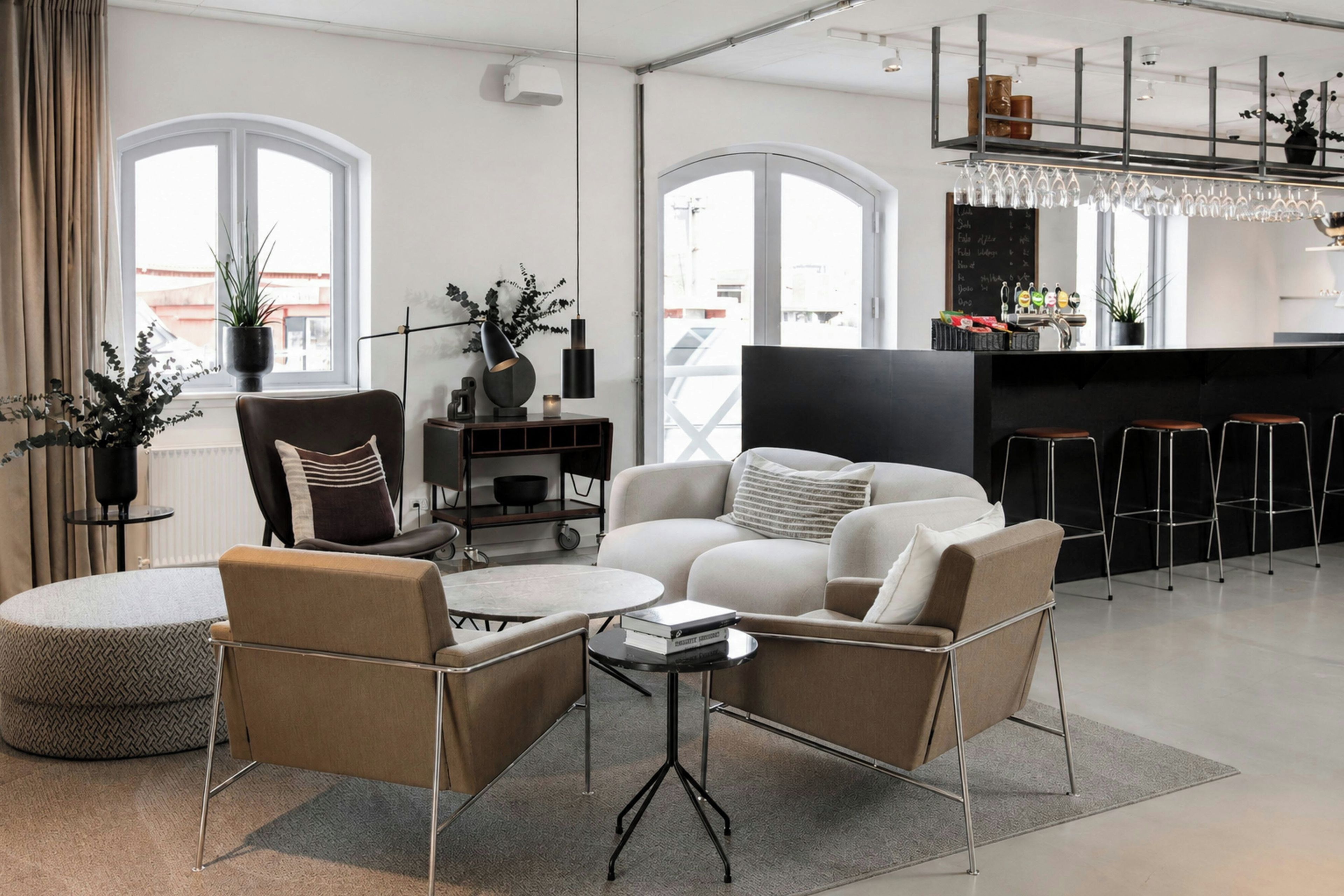 A modern living room with a sofa, chairs, a coffee table, and a kitchen area with bar stools.