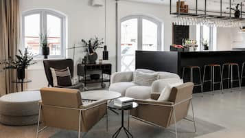 A modern living room with a sofa, chairs, a coffee table, and a kitchen area with bar stools.