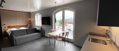 Una cocina moderna con comedor, un sofá y un ventanal con vistas a la ciudad.