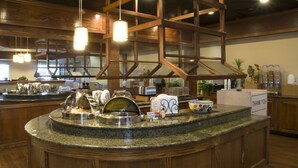 A buffet area with a wooden ceiling structure, buffet counters, and various food items. - Lamplighter Inn & Suites - North (Springfield)