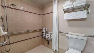 A bathroom with a shower, grab bars, a toilet, and a towel rack.