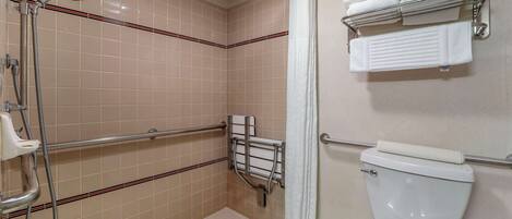 A bathroom with a shower, grab bars, a toilet, and a towel rack.