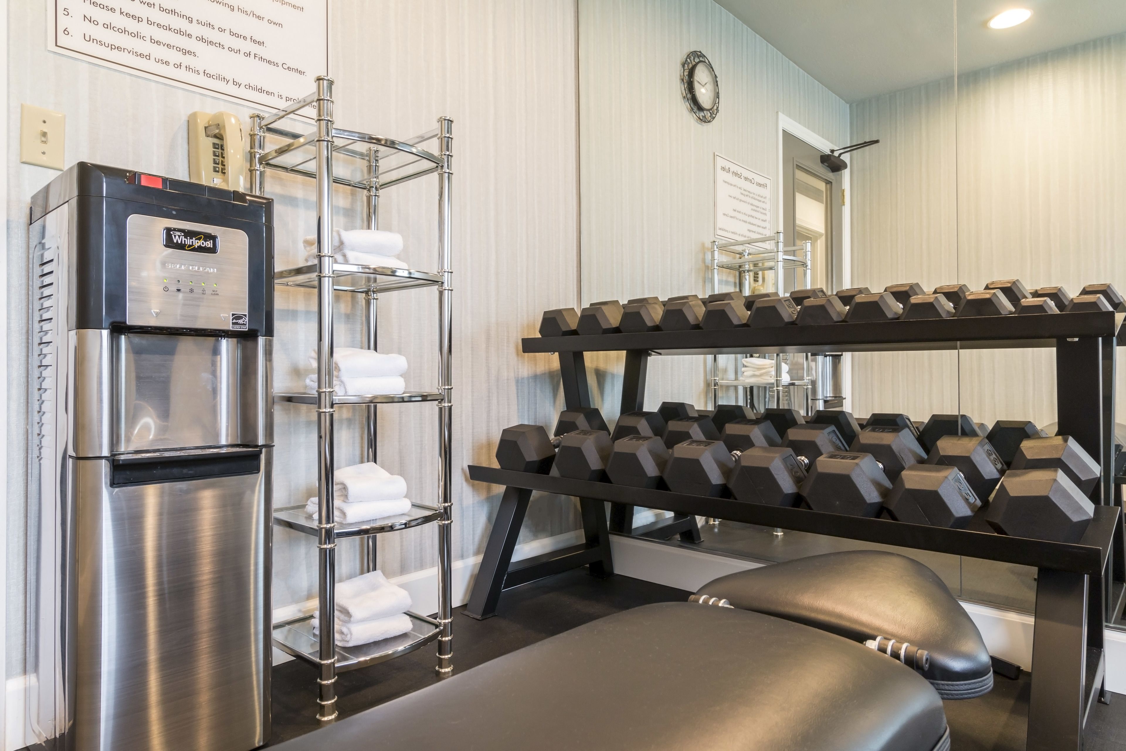 Ein Fitnessstudio mit Whirlpool-Wasserspender, einer Hantelbank und einer Sitzbank.