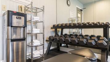 Ein Fitnessstudio mit Whirlpool-Wasserspender, einer Hantelbank und einer Sitzbank.
