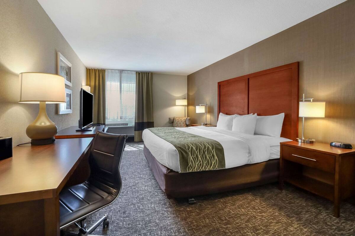 Ein Hotelzimmer mit einem Bett, Schreibtisch, Stuhl und zwei Nachttischlampen.
