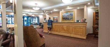 A lobby with a reception desk, a large painting, and a seating area with a leather couch and armchair.