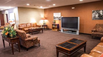 A living room with leather sofas, a coffee table, a TV, and a bookshelf.