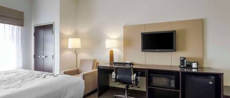Una habitación de hotel con cama, escritorio, silla, televisión y cafetera.