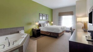 A hotel room with a large bed, a separate bathroom with a bathtub, a desk with a chair, and a television. - Sleep Inn & Suites Cave City (Cave City)