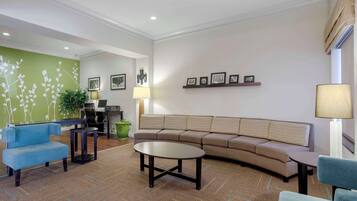 A modern living room with a blue sofa, a beige sectional, and a round coffee table.