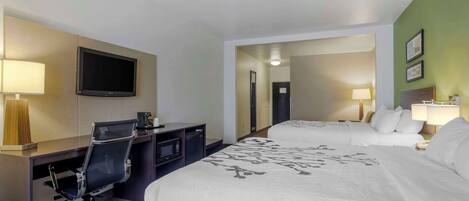 Una habitación de hotel con cama, escritorio, silla, televisor y microondas.