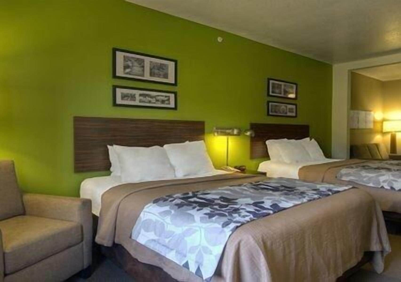 A hotel room with two beds, a wooden headboard, green walls, and framed pictures.