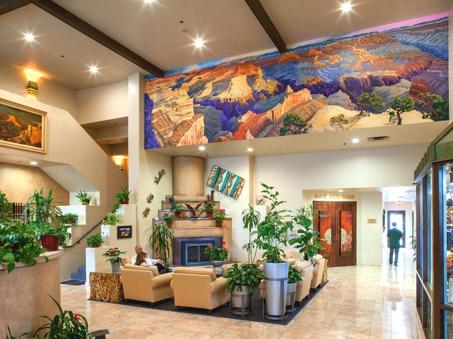 Un hall d’entrée spacieux, agrémenté d’une grande fresque murale, de plusieurs espaces de détente et d’une variété de plantes en pot.
