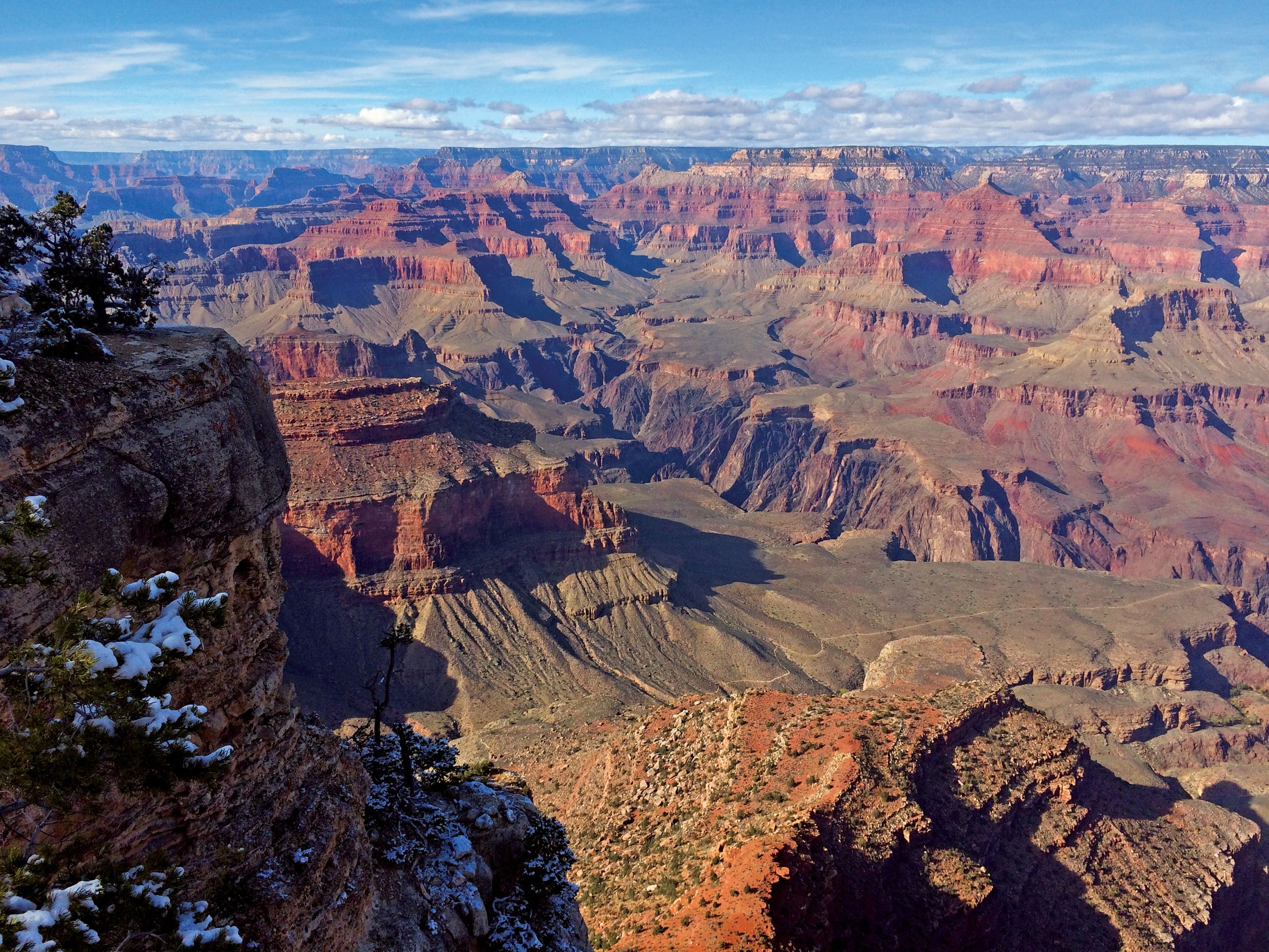 Een uitgestrekt canyonlandschap met gelaagde rotsformaties en schaarse begroeiing.