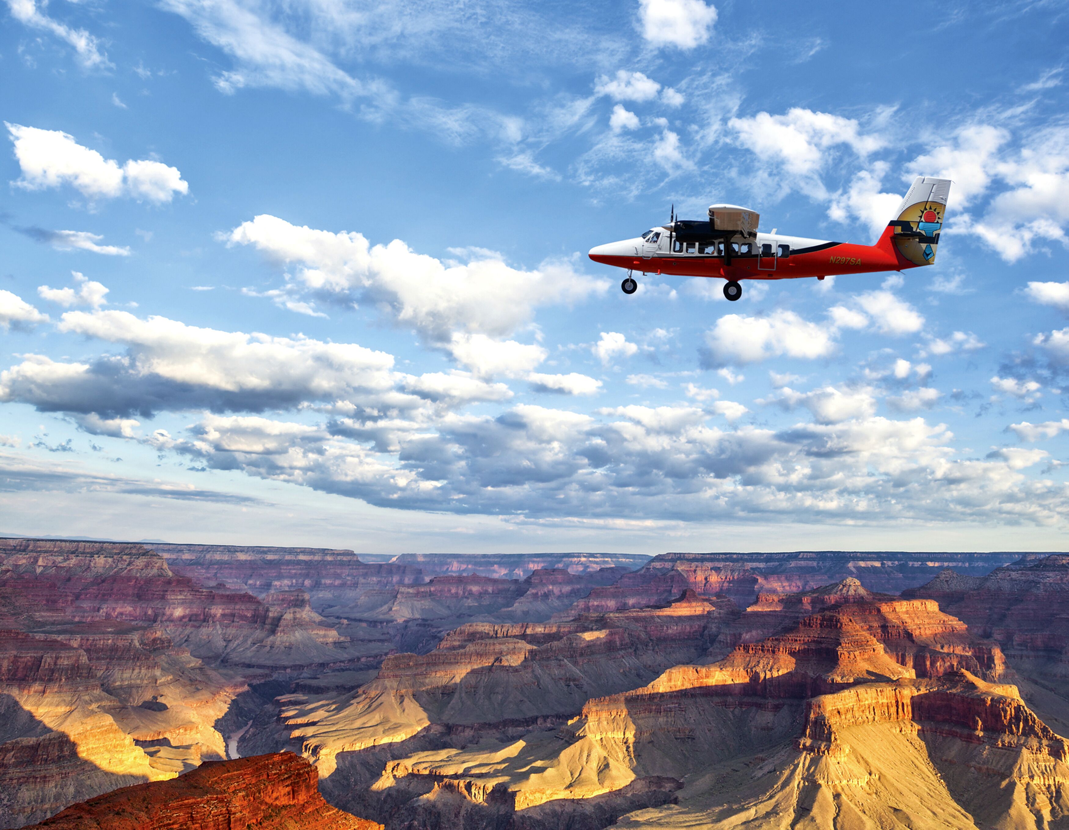 Un avion survole un canyon par un ciel dégagé.