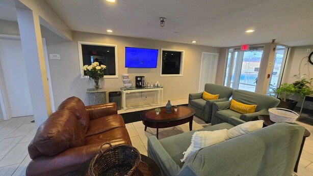 A modern living room with a brown leather sofa, a grey sofa with yellow cushions, a coffee table, and a TV mounted on the wall. - Copley Inn & Suites By OYO Akron OH (Akron)