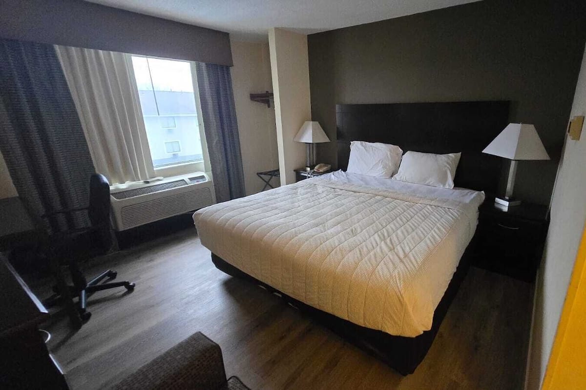 Une chambre d’hôtel avec un grand lit, deux tables de chevet avec des lampes, un bureau et une chaise.