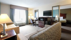 A hotel room with a sofa, a desk with a computer, a television, and a bed. - Copley Inn & Suites By OYO Akron OH (Akron)