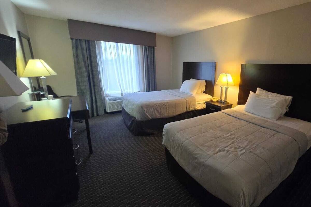 Une chambre d’hôtel avec deux lits, un bureau et une chaise.