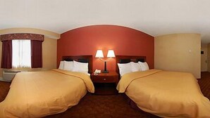 A hotel room with two single beds, a nightstand with a lamp, and a window with curtains. - The Landing at Laguardia (East Elmhurst)