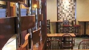 A restaurant interior with wooden tables and chairs, a checkered wall, and a modern light fixture. - The Landing at Laguardia (East Elmhurst)