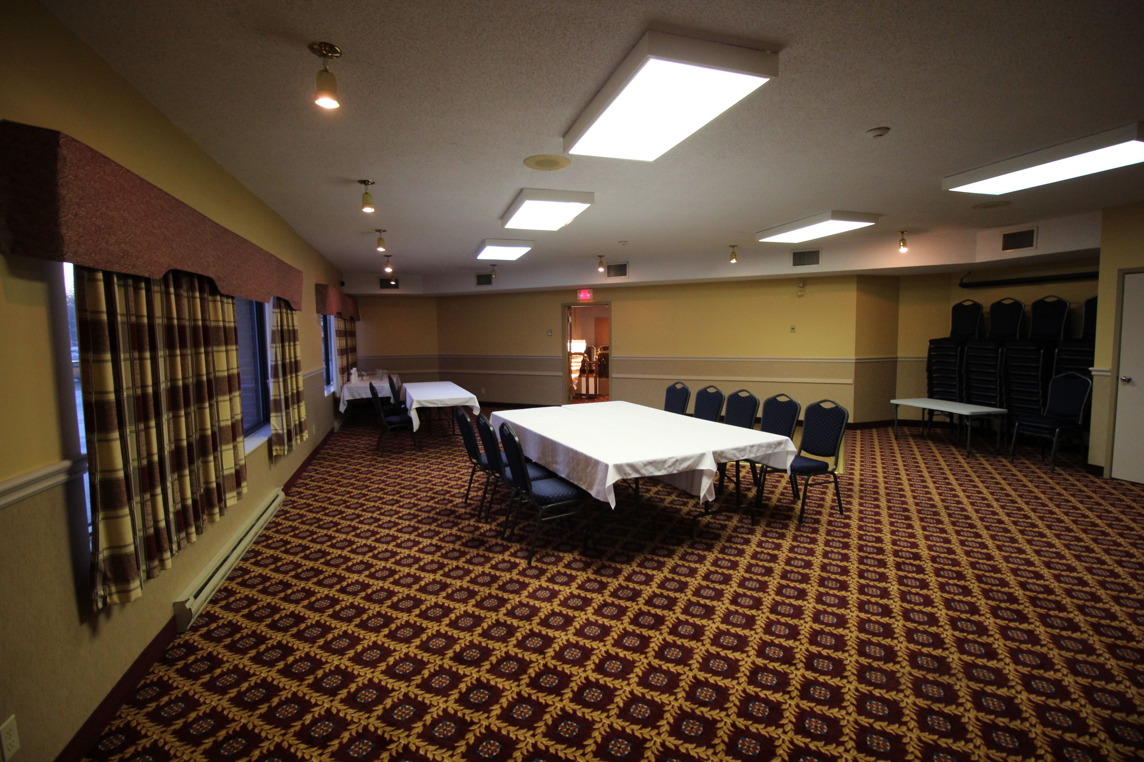 A conference room with a patterned carpet, white tables, and chairs.