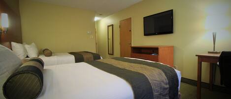 A hotel room with two beds, a television, a desk, and a lamp.