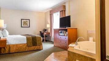 A hotel room with a bed, a desk, a television, a microwave, a sink, and a large window.