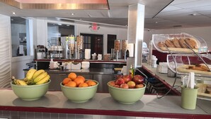 Un bufé de desayuno con tazones de fruta, una estación de café y una exhibición de pasteles.