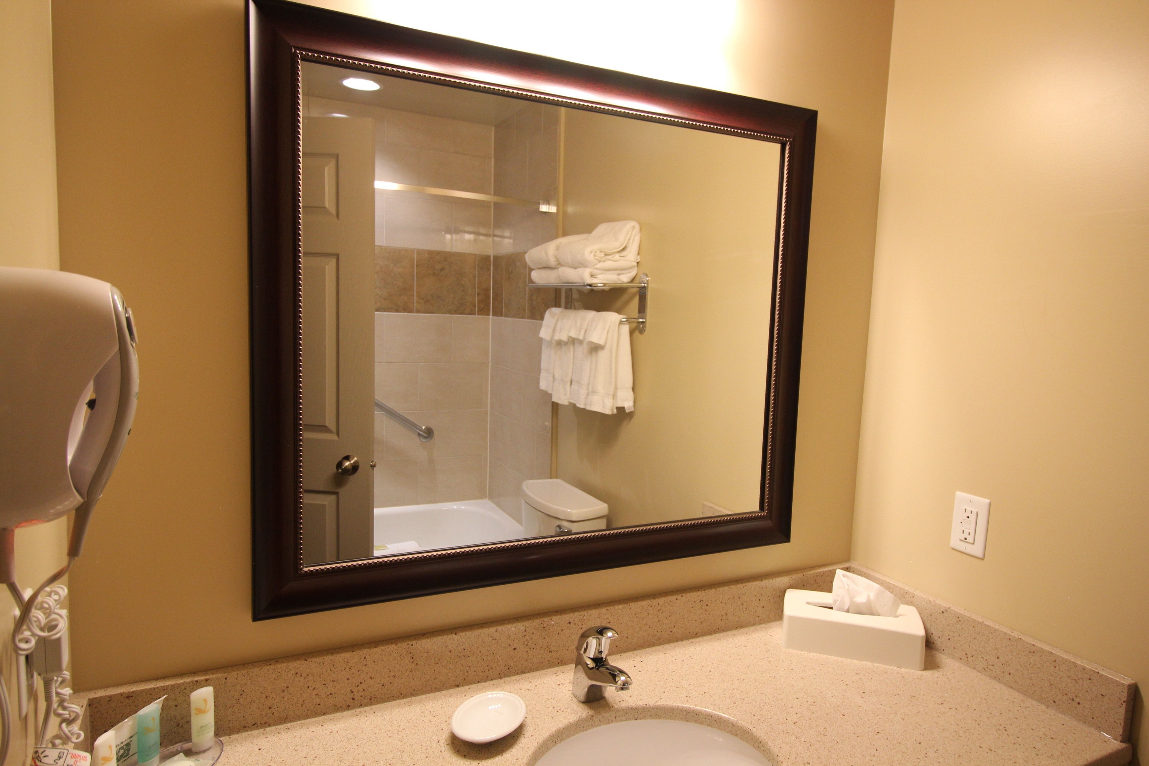 A bathroom with a large mirror, a sink, a towel rack, and a hairdryer.