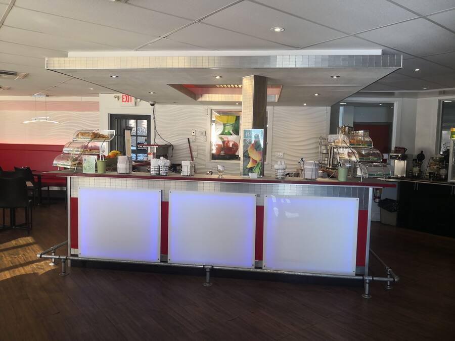 Ein modernes Café mit einer Theke, auf der Gebäck und Kaffeemaschinen präsentiert werden.