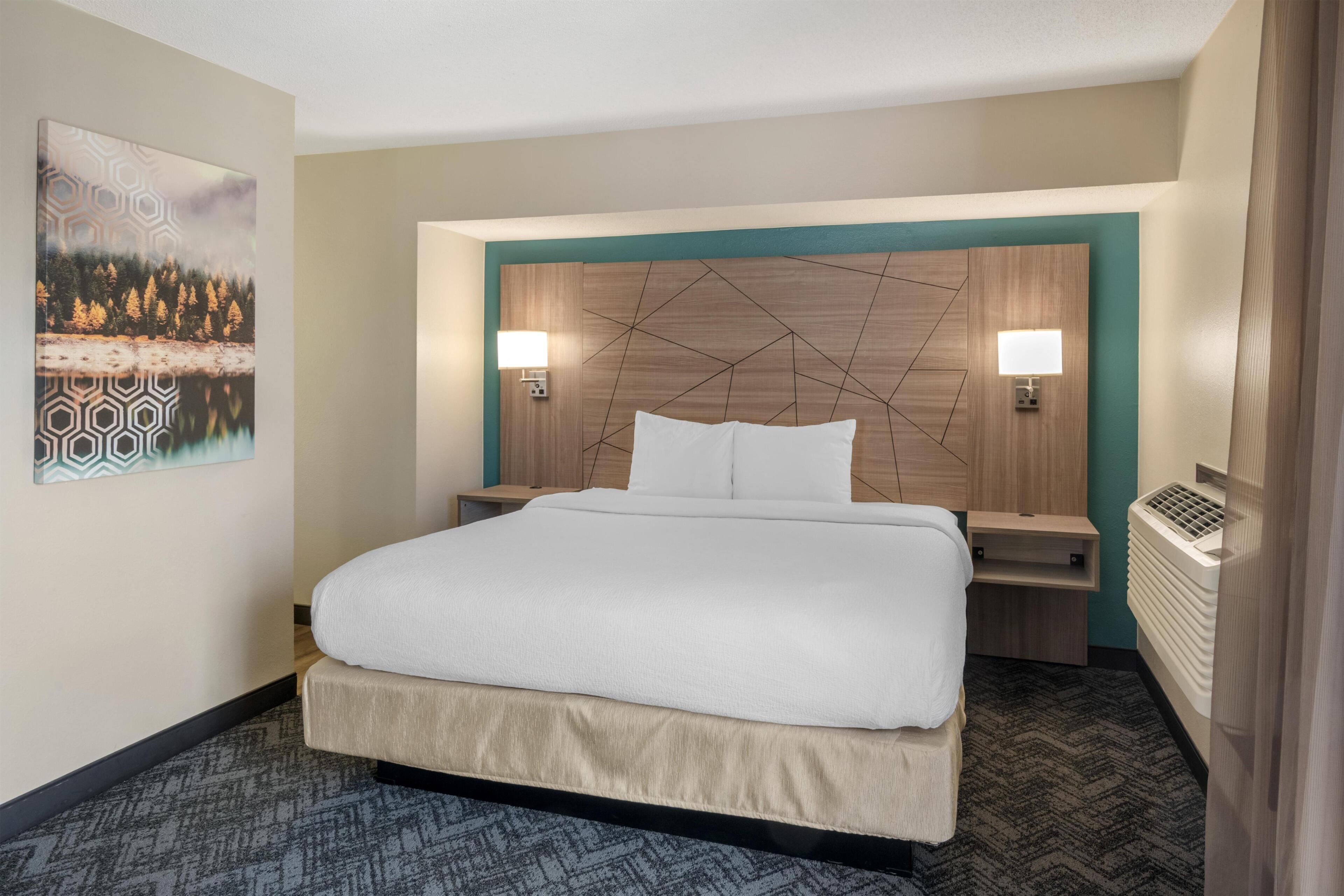 Ein Hotelzimmer mit einem großen Bett, zwei Nachttischen, einer Wandlampe und einem Heizkörper.
